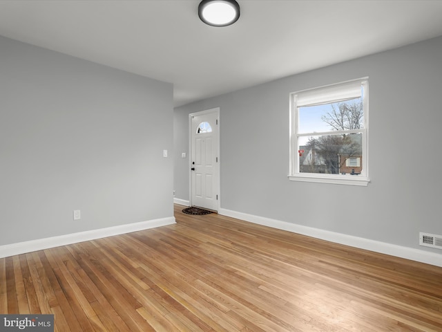 spare room featuring baseboards, visible vents, and light wood finished floors