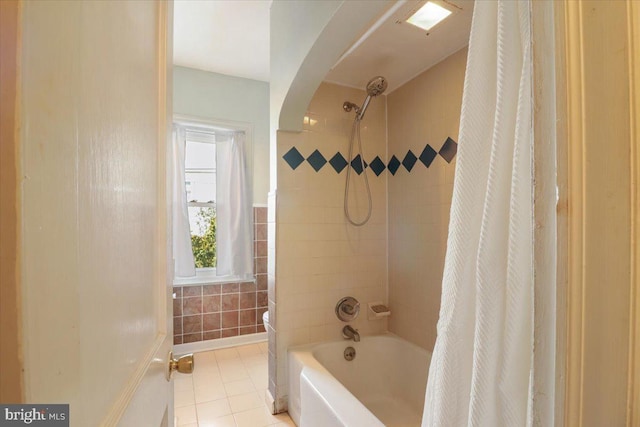 bathroom with shower / tub combo with curtain, tile patterned floors, toilet, and tile walls