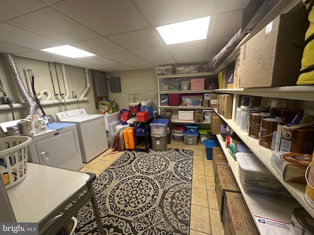 laundry area with light tile patterned floors, washing machine and dryer, and electric panel