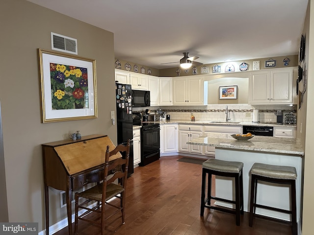 kitchen featuring sink, white cabinetry, light stone counters, black appliances, and decorative backsplash