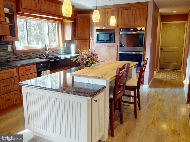 kitchen featuring stainless steel appliances, tasteful backsplash, light wood-type flooring, and a kitchen island