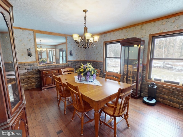 dining room with a wainscoted wall, an inviting chandelier, a textured ceiling, plenty of natural light, and wallpapered walls