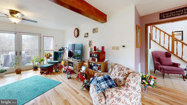 living area featuring wood finished floors, beamed ceiling, french doors, and stairs