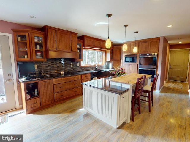 kitchen with double oven, light wood finished floors, backsplash, and built in microwave