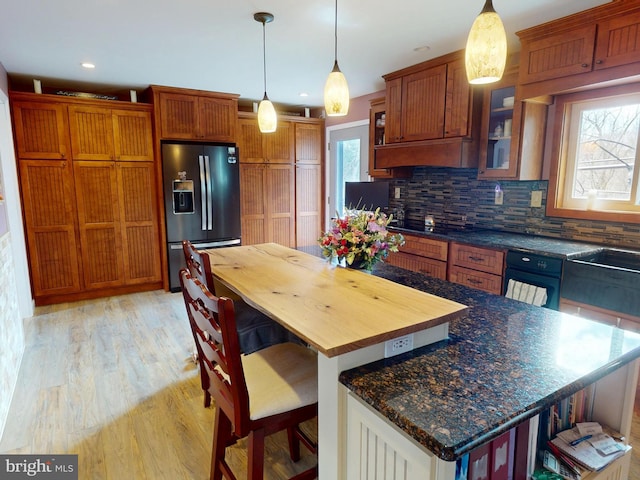 kitchen featuring light wood-style floors, glass insert cabinets, plenty of natural light, and stainless steel fridge with ice dispenser