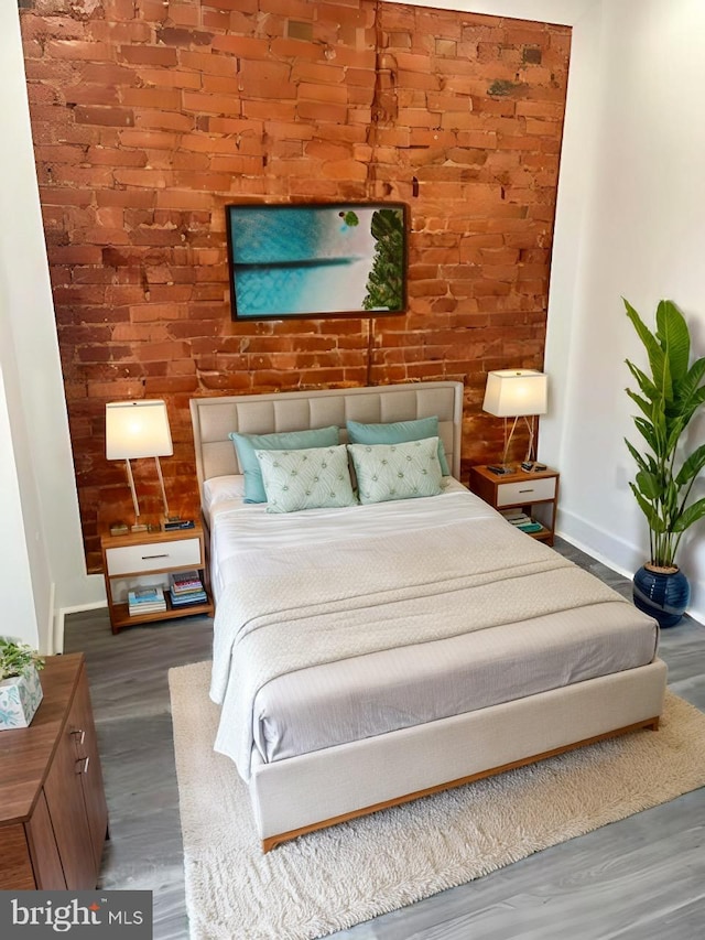 bedroom with hardwood / wood-style flooring and brick wall