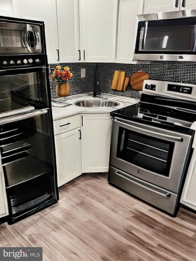 kitchen with appliances with stainless steel finishes, sink, white cabinets, and decorative backsplash