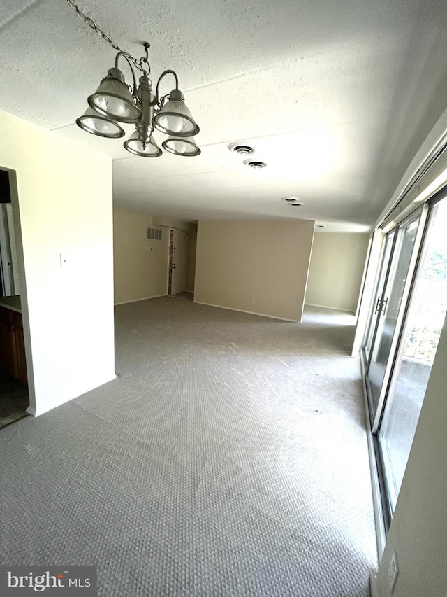 carpeted empty room with visible vents and a textured ceiling