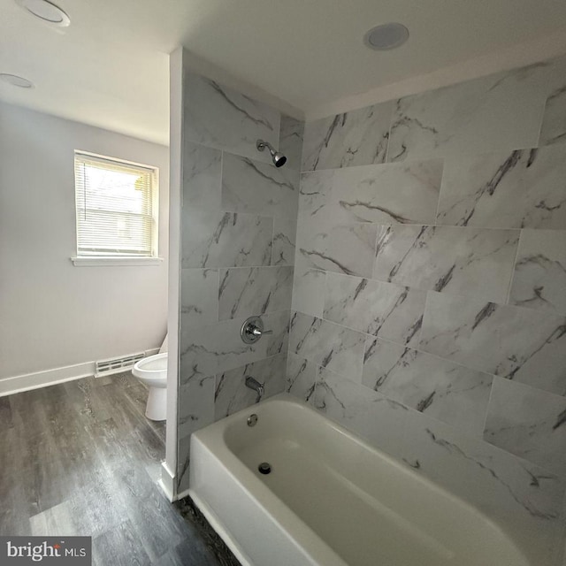 bathroom featuring wood-type flooring, toilet, and tiled shower / bath combo