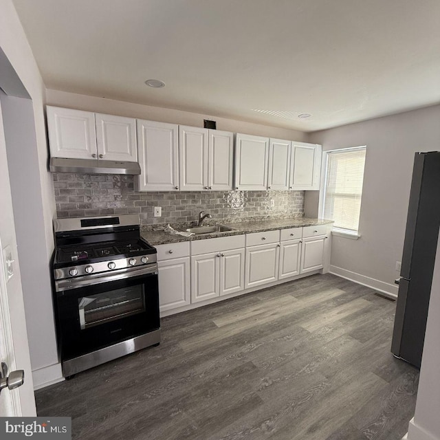 kitchen with white cabinetry, stone countertops, appliances with stainless steel finishes, dark hardwood / wood-style floors, and backsplash