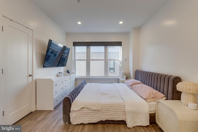 bedroom with radiator heating unit, light wood-style flooring, and recessed lighting