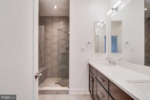 bathroom with double vanity, a stall shower, tile patterned flooring, and a sink