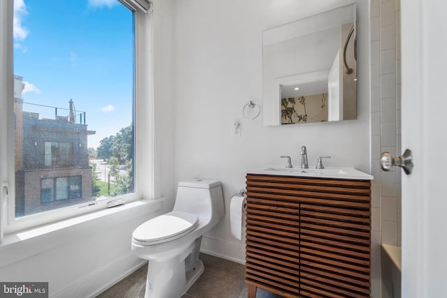 bathroom featuring toilet, baseboards, and vanity