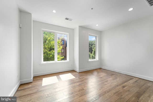 spare room with baseboards, wood-type flooring, visible vents, and recessed lighting