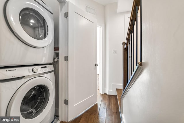 laundry area with laundry area, hardwood / wood-style flooring, stacked washing maching and dryer, and visible vents