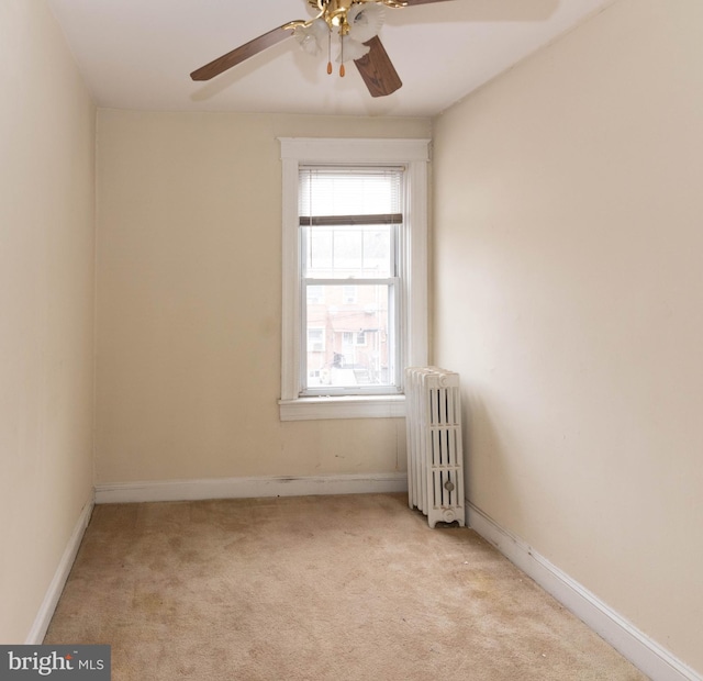 carpeted empty room featuring ceiling fan and radiator