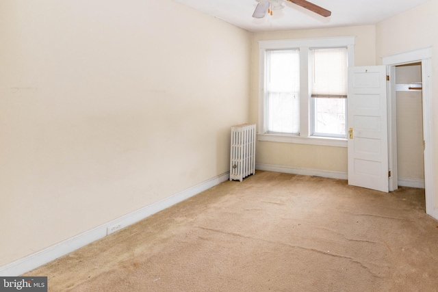 carpeted empty room featuring radiator heating unit and ceiling fan