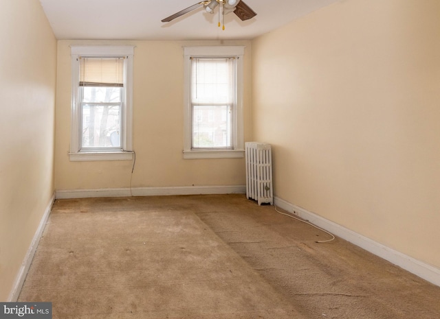 carpeted spare room featuring radiator and ceiling fan