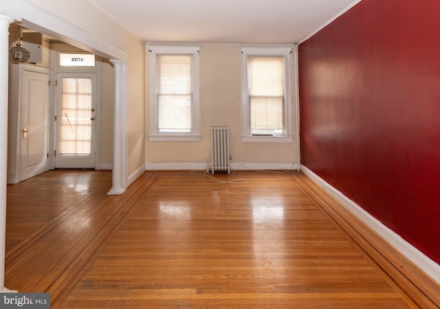 interior space with ornate columns, wood-type flooring, and radiator heating unit