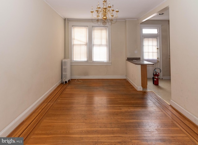 unfurnished dining area featuring radiator, a wealth of natural light, and dark wood-type flooring