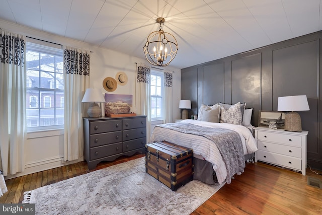 bedroom with multiple windows, hardwood / wood-style flooring, crown molding, and a chandelier