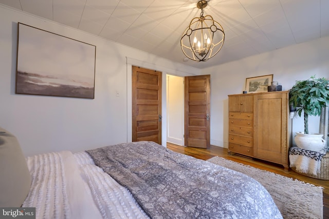 bedroom with an inviting chandelier, ornamental molding, and wood-type flooring