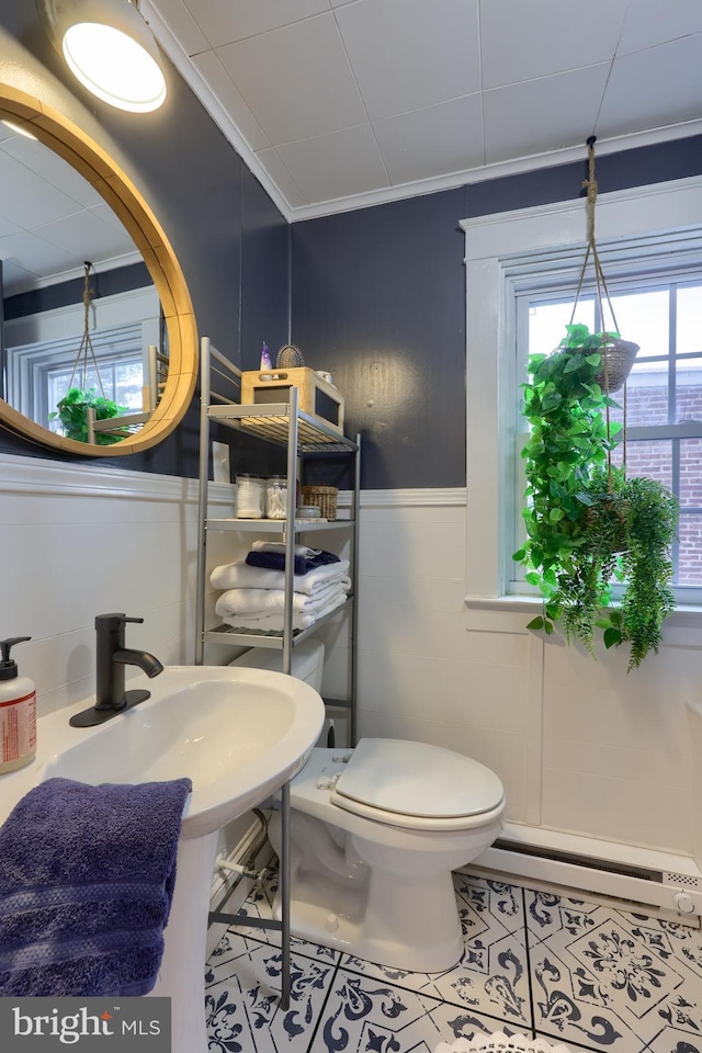 bathroom with crown molding, tile patterned floors, toilet, and a baseboard heating unit