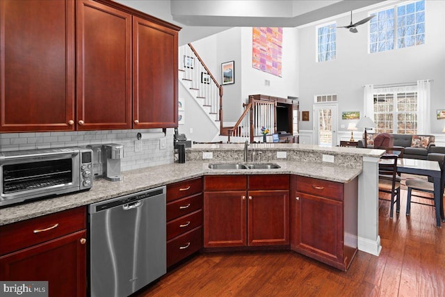 kitchen with dark wood-type flooring, stainless steel dishwasher, light stone countertops, and sink