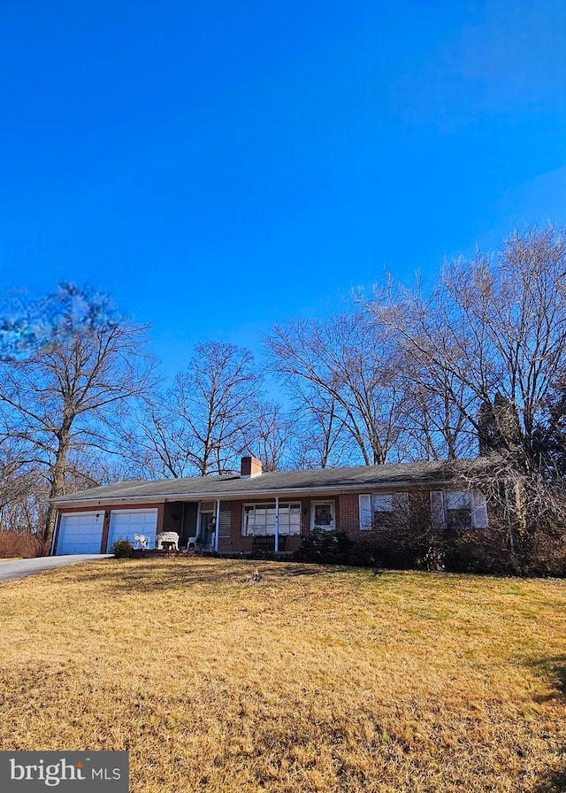 ranch-style house with brick siding, a chimney, an attached garage, and a front yard