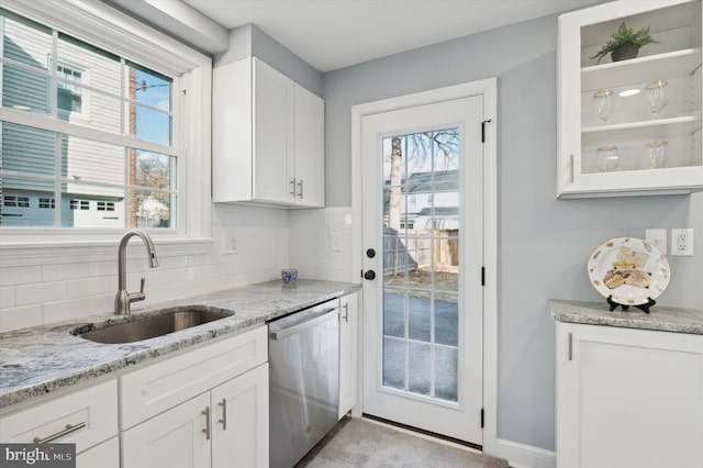 kitchen with sink, tasteful backsplash, light stone countertops, white cabinets, and stainless steel dishwasher