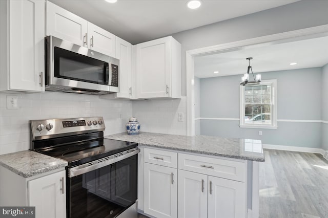 kitchen with appliances with stainless steel finishes, white cabinetry, backsplash, light hardwood / wood-style floors, and kitchen peninsula