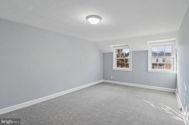 additional living space featuring carpet floors and vaulted ceiling