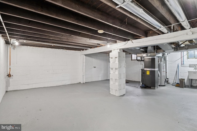 basement with heating unit, a wealth of natural light, and gas water heater