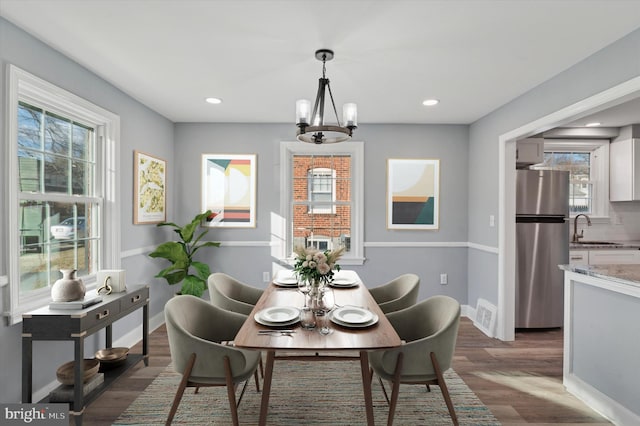 dining space with sink, an inviting chandelier, and dark hardwood / wood-style flooring