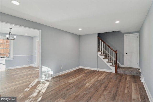 unfurnished living room featuring hardwood / wood-style flooring and a chandelier