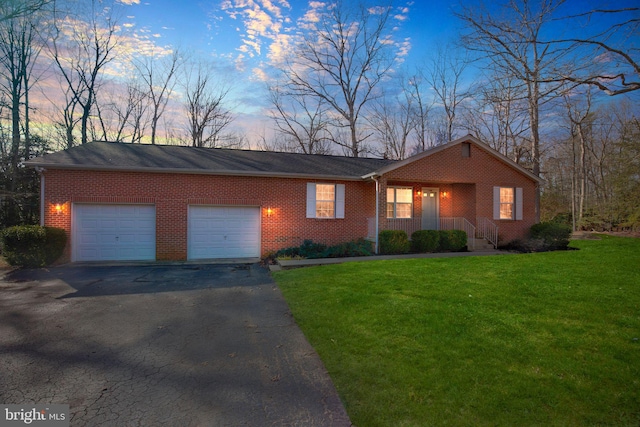 single story home featuring a garage and a lawn