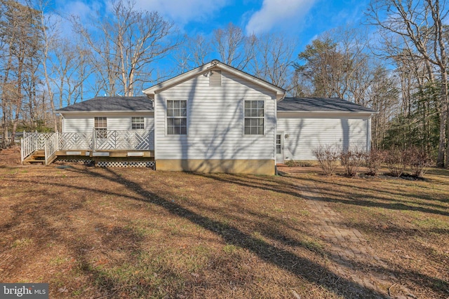 back of property with a wooden deck and a lawn