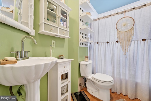 bathroom with hardwood / wood-style floors, toilet, and a shower with shower curtain