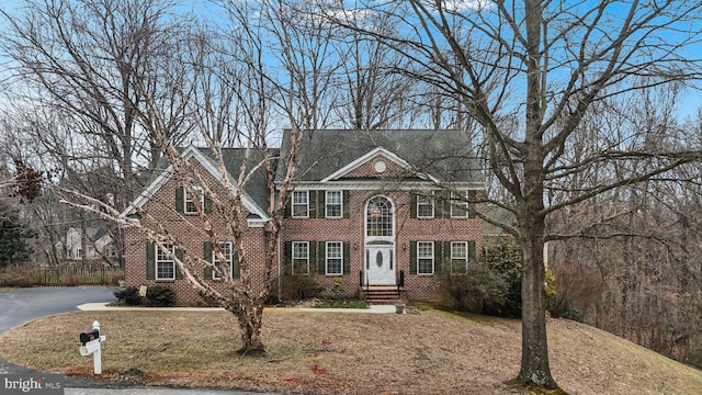 colonial inspired home featuring brick siding and driveway