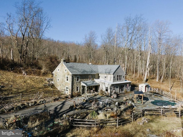 back of house with a storage shed