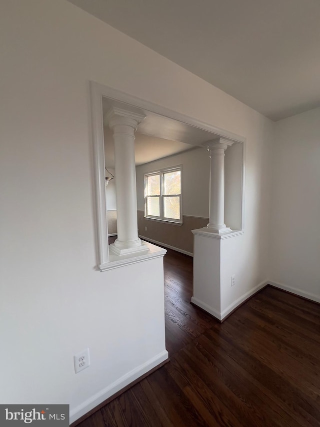 empty room with dark hardwood / wood-style floors and ornate columns