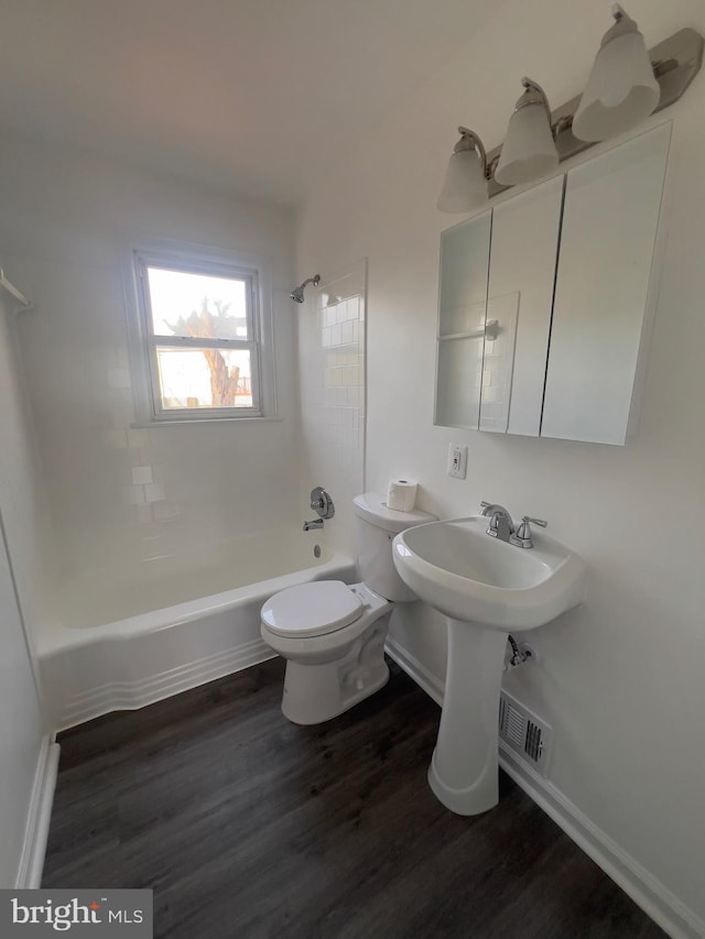 bathroom featuring tiled shower / bath combo, wood-type flooring, and toilet