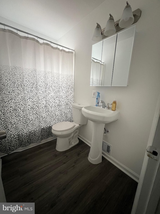 bathroom with hardwood / wood-style flooring, toilet, and curtained shower