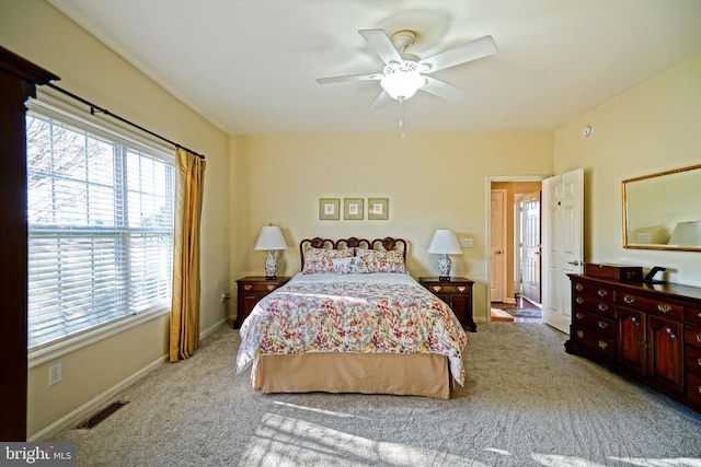 carpeted bedroom featuring a ceiling fan, visible vents, and baseboards