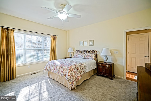 bedroom featuring light carpet, baseboards, visible vents, and a ceiling fan