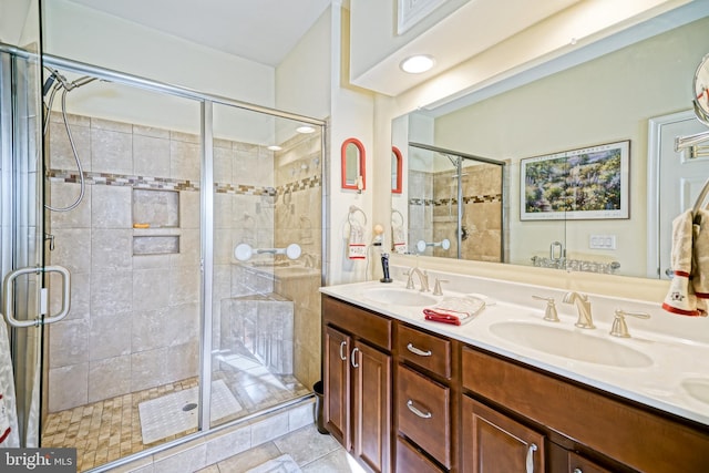 full bath featuring double vanity, a sink, and a shower stall