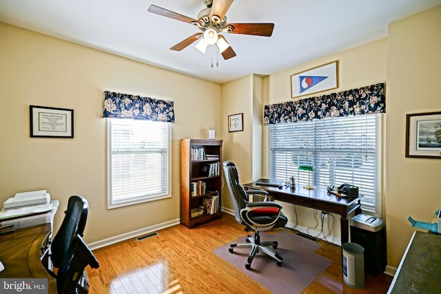 office featuring ceiling fan, wood finished floors, visible vents, and baseboards