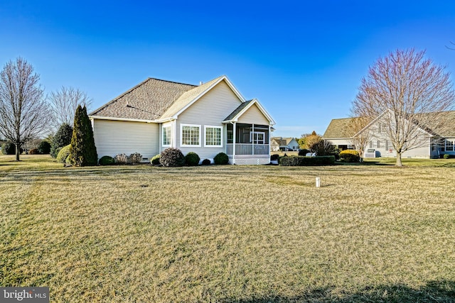 ranch-style house featuring a sunroom, a shingled roof, and a front yard