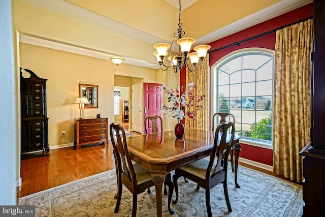 dining space with a chandelier, baseboards, and wood finished floors