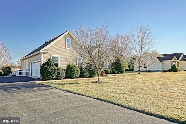 view of side of property featuring driveway, an attached garage, and a yard